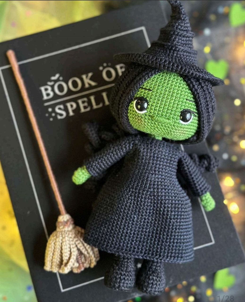 Crocheted witch doll with broom and spellbook, showcasing its charming design and vibrant colors.