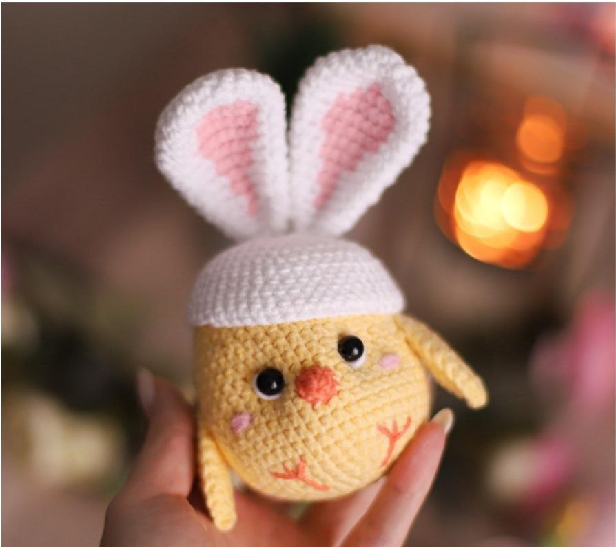 Yellow crochet chick with a white bunny ear hat, showcasing a charming and colorful design, perfect for cute and creative decorations.