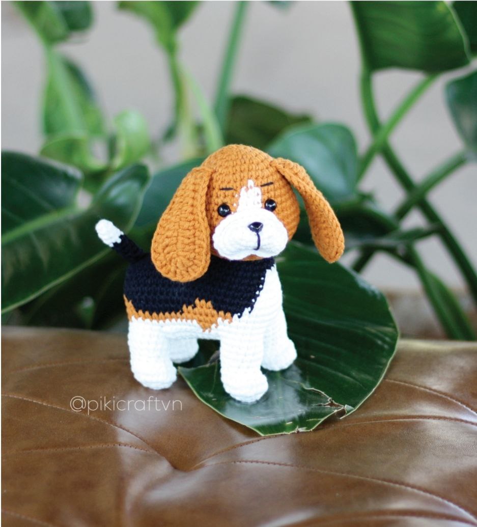 Crochet Beagle dog sitting on a chair, showcasing its detailed design and vibrant colors.