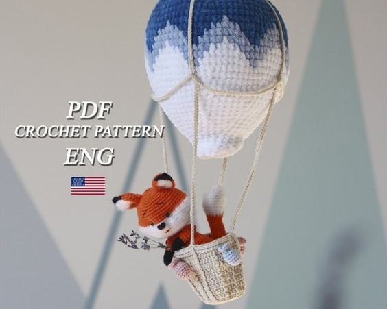 Crocheted fox inside a hot air balloon, featuring a charming and detailed design.