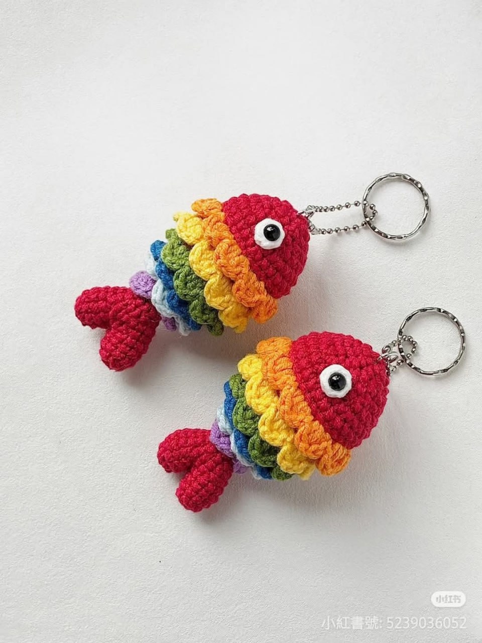 Two crochet fish keychains in rainbow colors, showcasing their vibrant and eye-catching design.