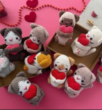 Several crocheted cat figures with hearts, carefully arranged in a box, highlighting their creativity and detail for Valentine's Day.