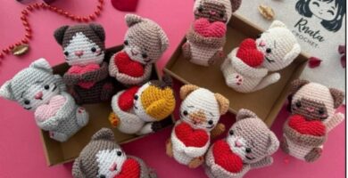 Several crocheted cat figures with hearts, carefully arranged in a box, highlighting their creativity and detail for Valentine's Day.