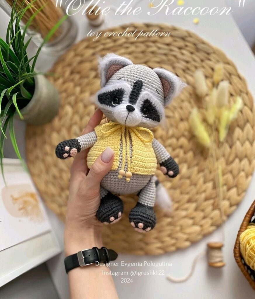Raccoon with a yellow sweater, entirely crocheted, displaying a curious and playful expression.